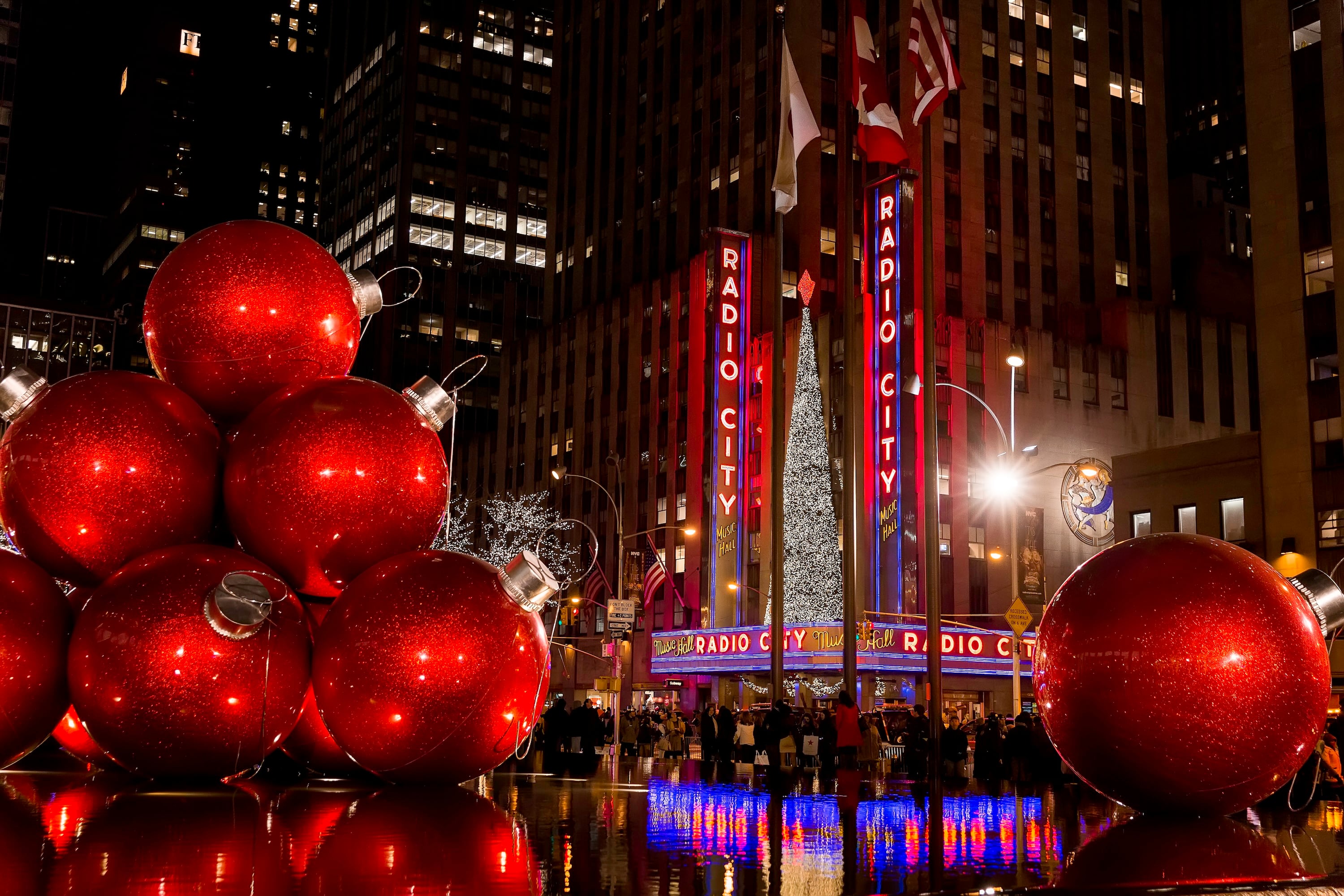 Giant red Christmas ornaments outside the illuminated Radio City Music Hall.