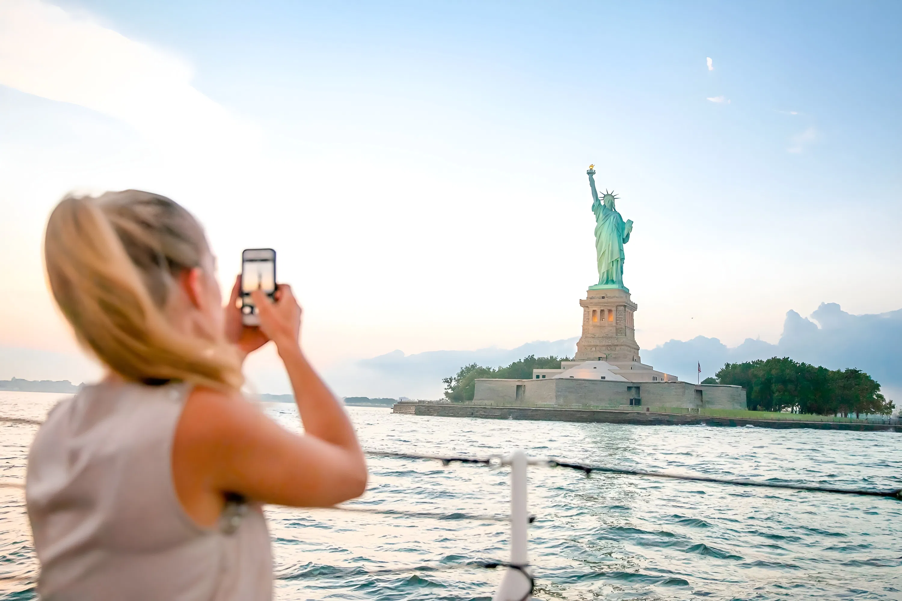 A passenger photographs the Statue of Liberty from a sightseeing boat